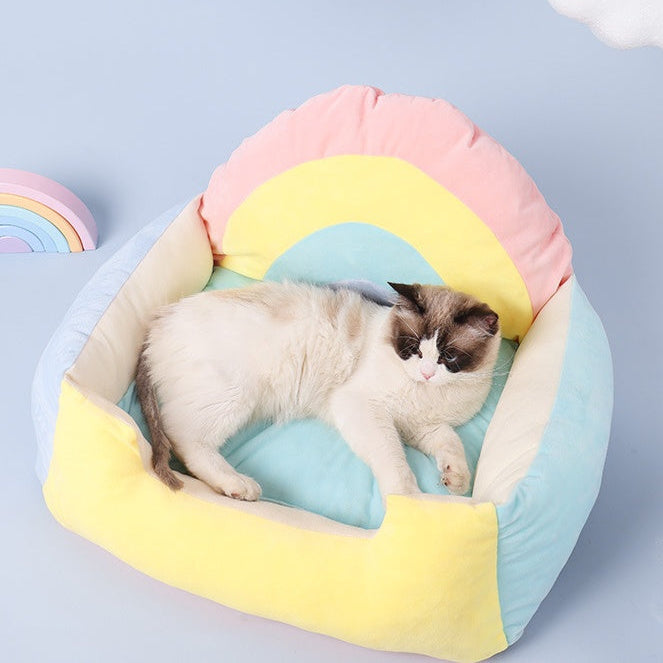Cat lying on a colorful rainbow-shaped pet bed against a light blue background