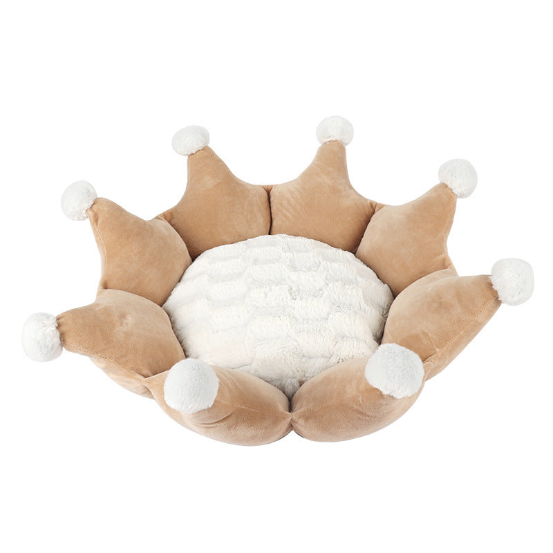 Beige crown-shaped pet bed with white cushion and pom-poms on a white background