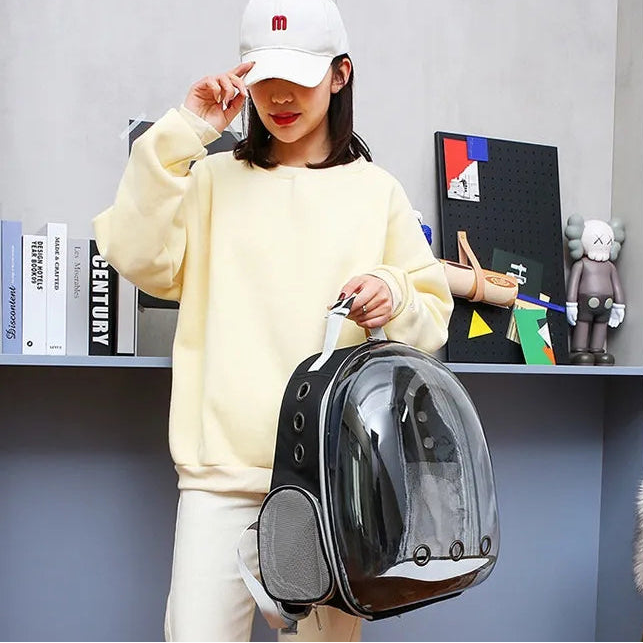 Person holding a black transparent backpack with bubble design in an indoor setting.