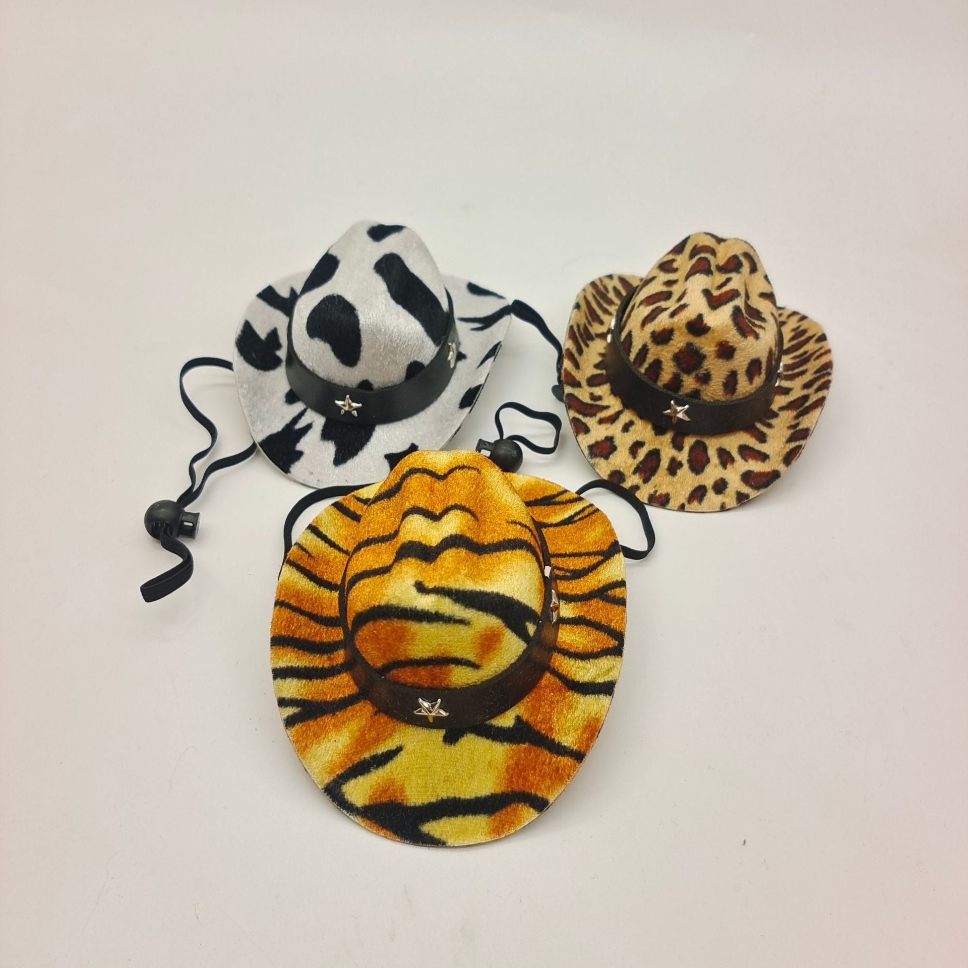 Three animal print pet cowboy hats on a light gray background