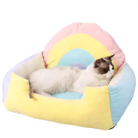 Cat lying on a rainbow coloured pet bed shaped like a rainbow on a white background.
